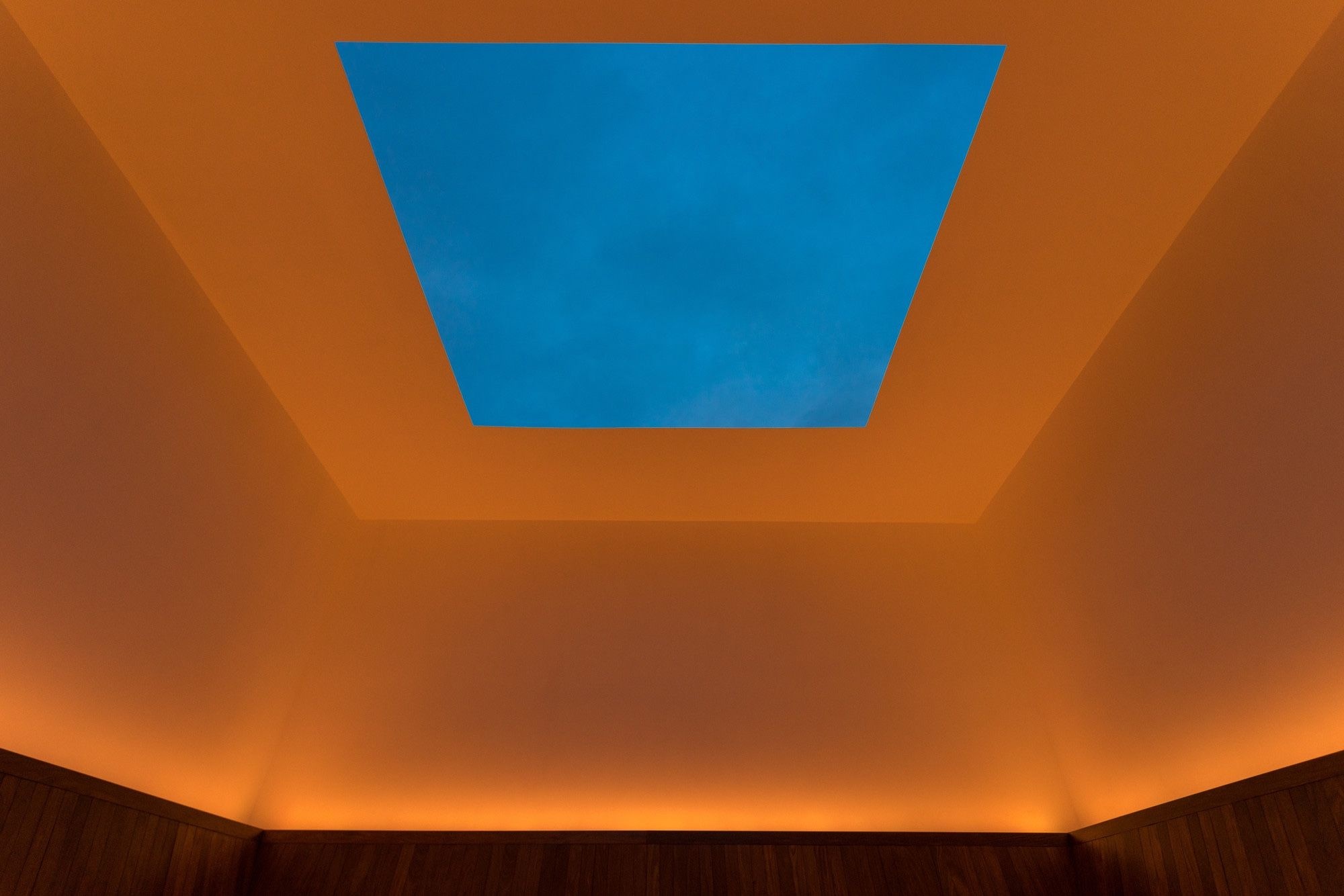 James Turrell’s Meeting at MoMA PS1, a square of blue sky framed by a ceiling and walls washed in amber light above a timber bench, Long Island City, New York | The Aficionados
