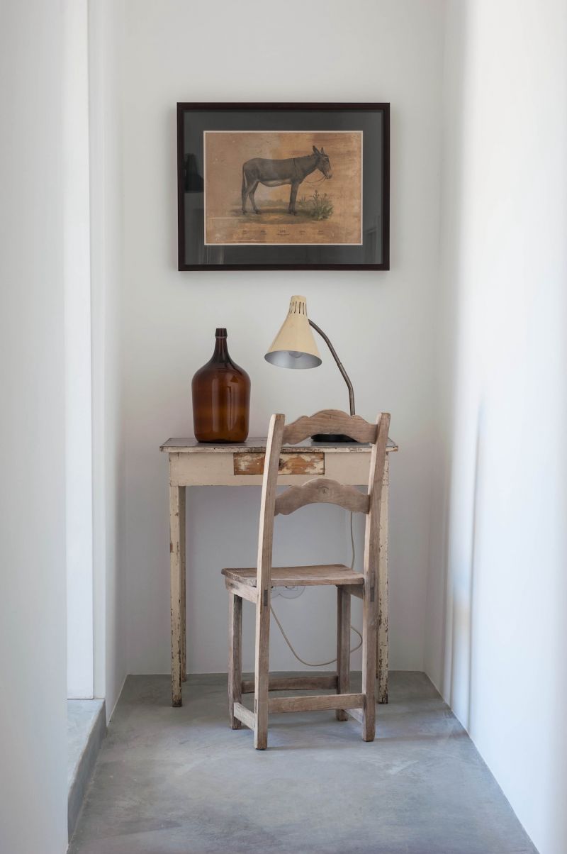 Pensão Agrícola, Tavira, Algarve: rustic corner with vintage desk, demijohn lamp and donkey portrait, minimal-intervention restoration by Atelier RUA.