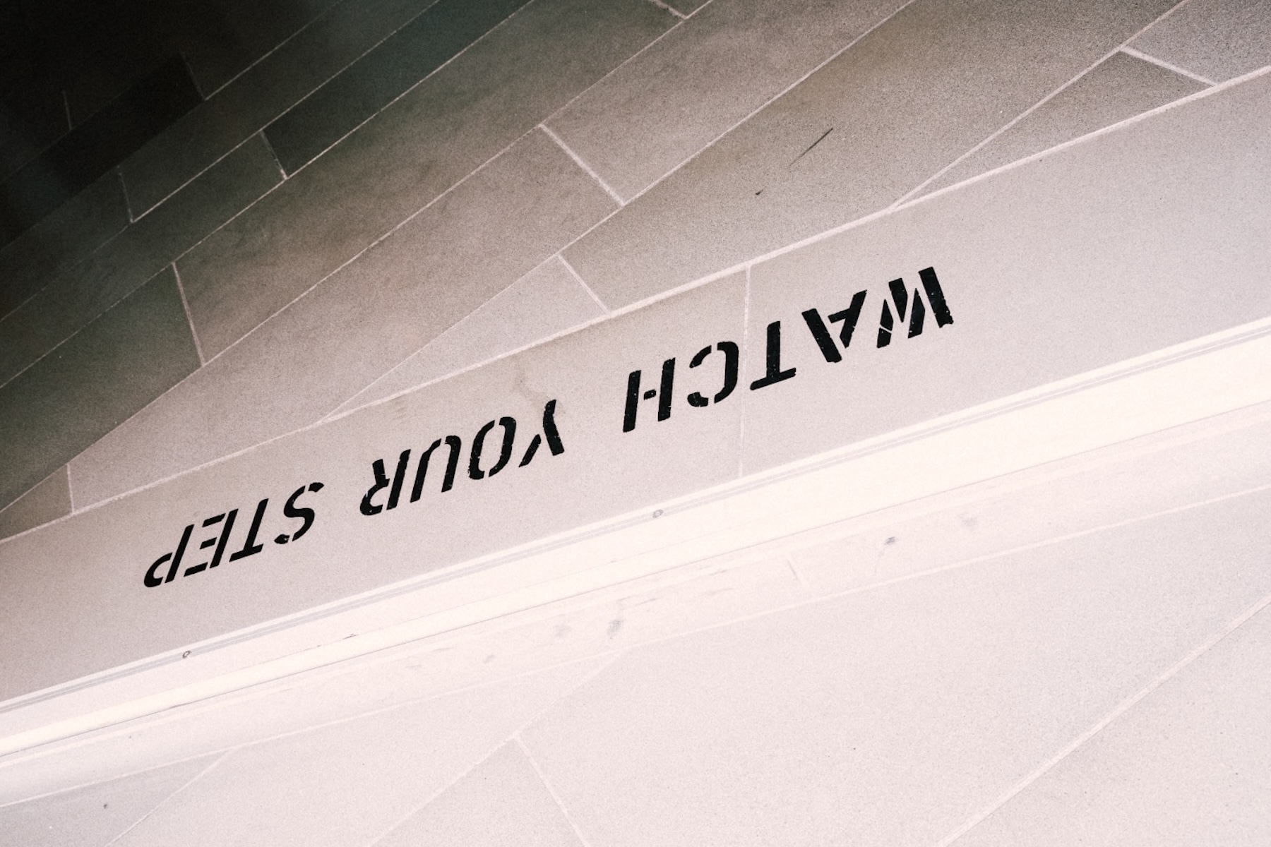 Watch Your Step stencilled in black on the stone stair at the Arthotel Blaue Gans, Salzburg | The Aficionados