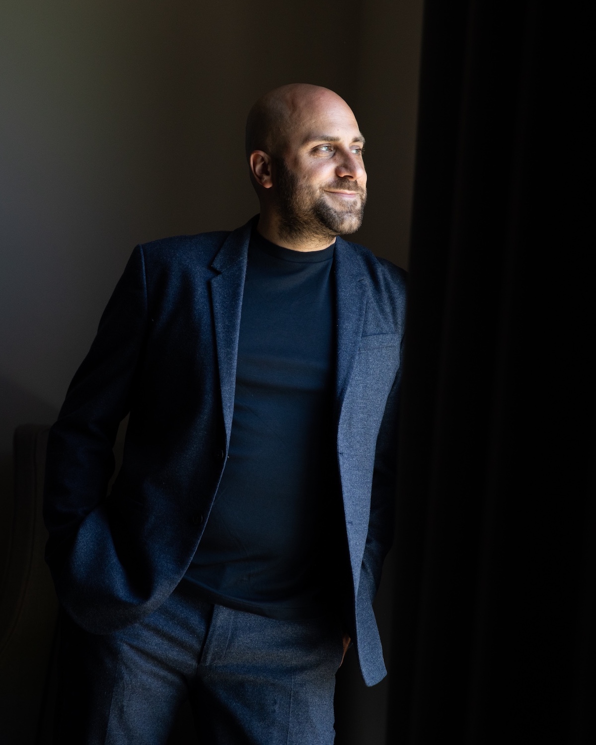 Alessandro Sironi | Hotelier, Italian man in blue suit looking towards light |  