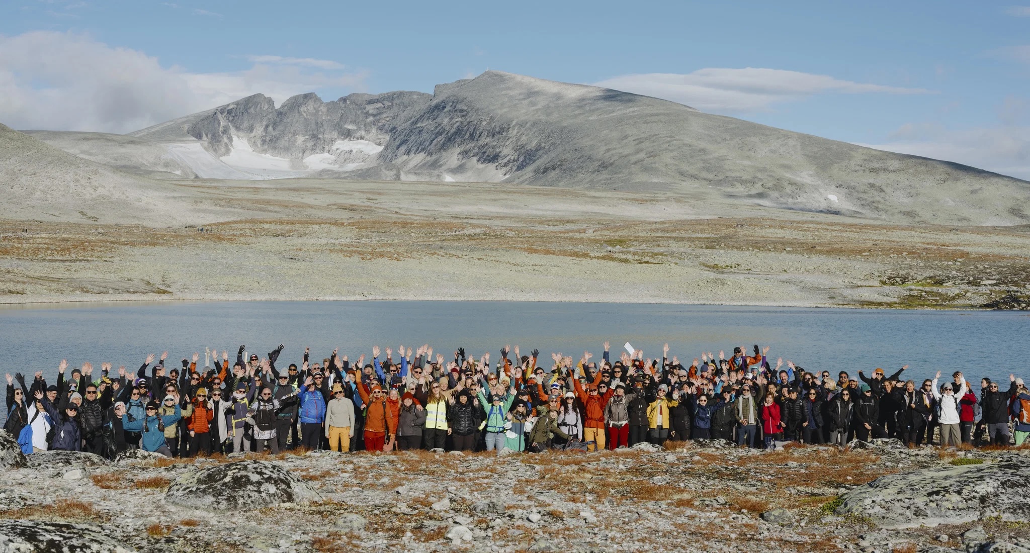 A large group with arms raised beside a lake below the Snøhetta massif in Dovrefjell, the Norwegian peak that gave the studio its name | The Aficionados