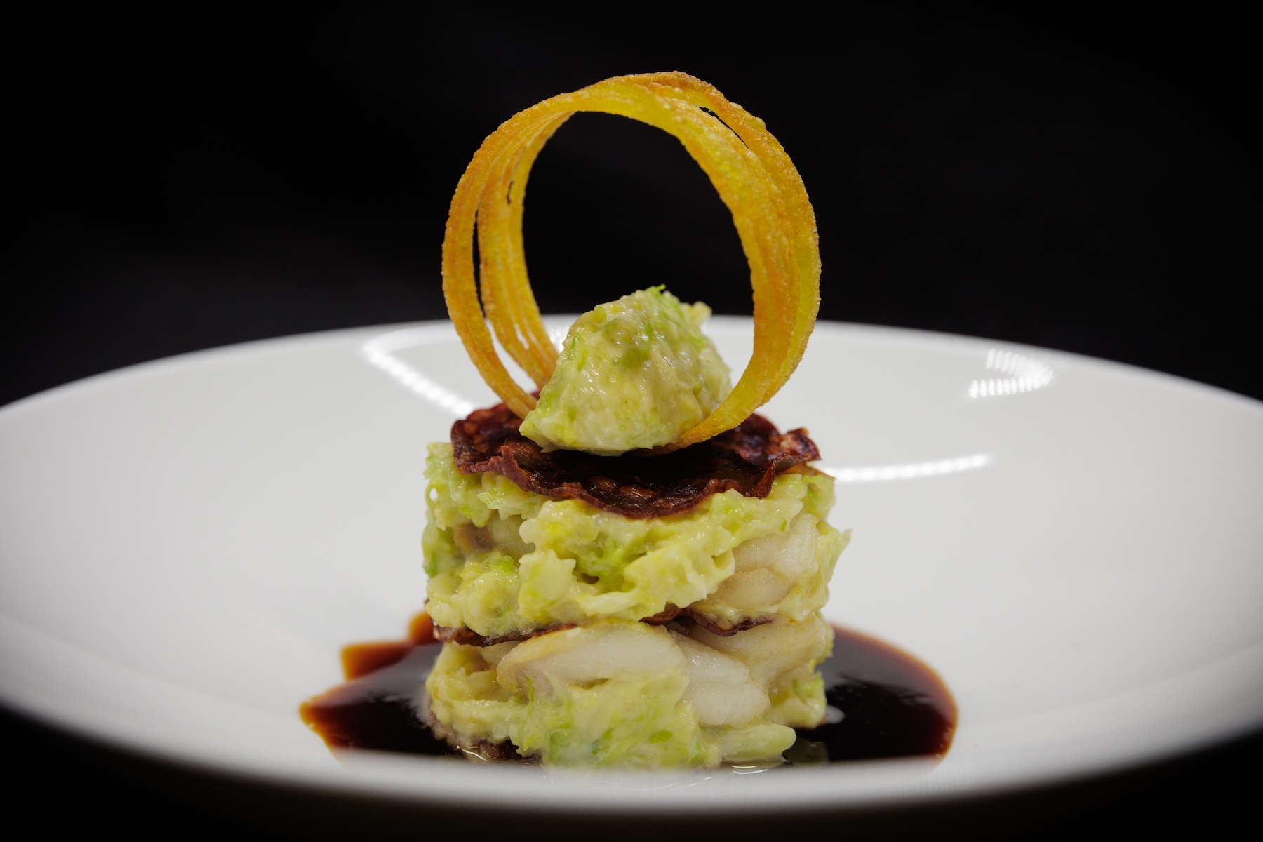 A layered dish of fish, savoy cabbage and crisp pancetta with a fried potato ring, plated at the Kantine Rosine, Hotel Goldene Rose | The Aficionados