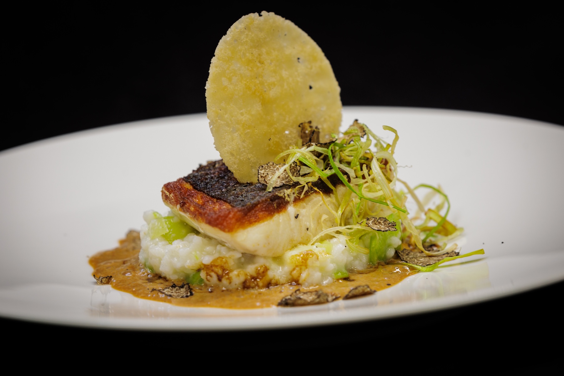 Crisp-skinned fish on creamed leek risotto with shaved truffle and a potato crisp, from the tasting menu at the Kantine Rosine | The Aficionados