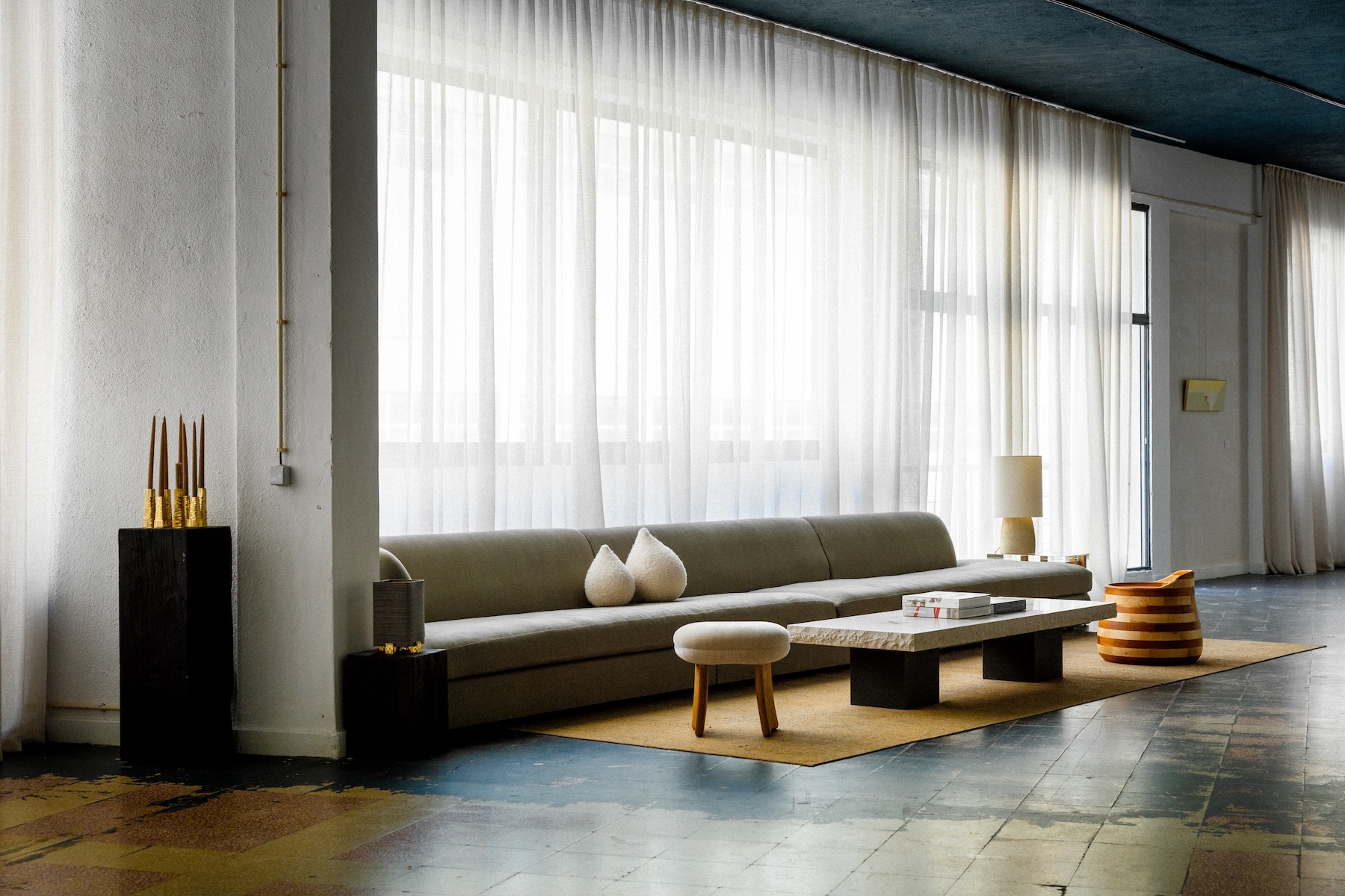 Minimalist lounge with long grey sofa, stone coffee table and handcrafted objects, Lisbon Design Week 2026