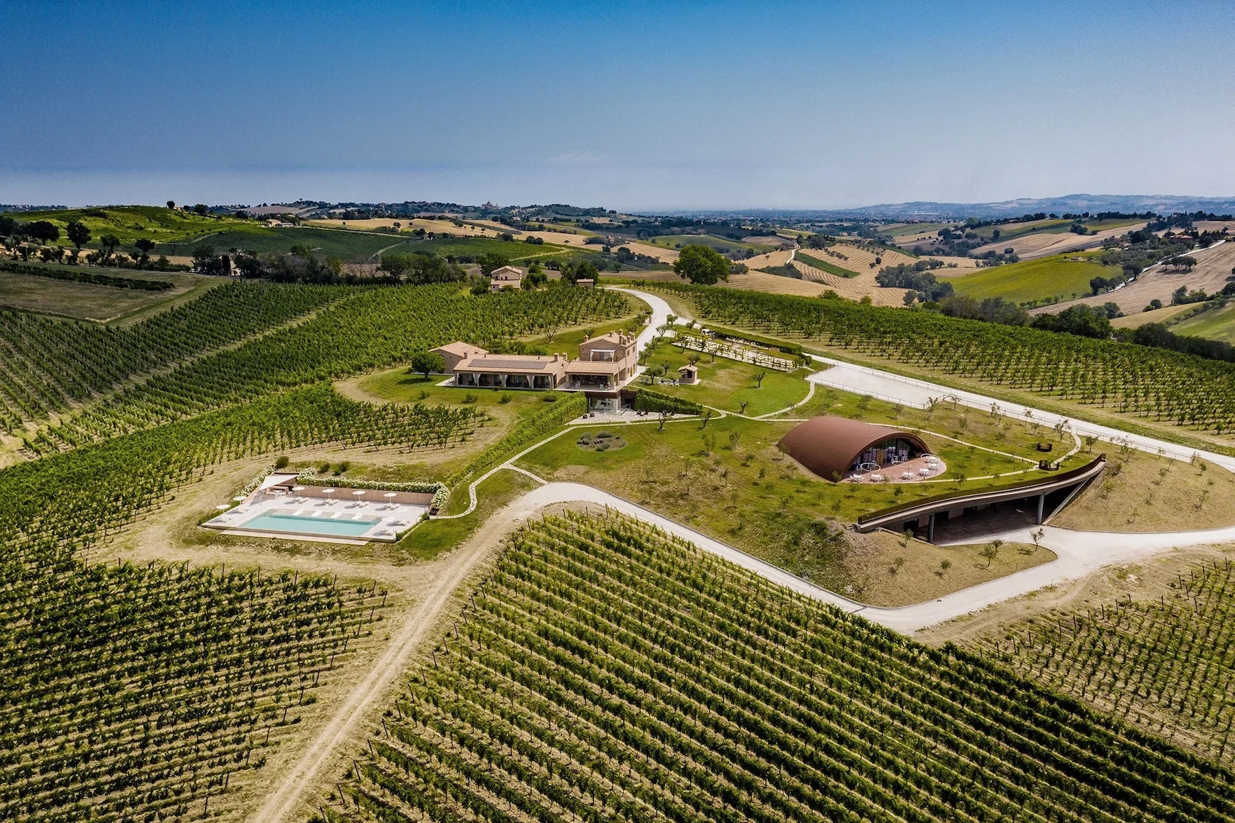 Aerial view acorss Le Marche rich green rolling hills countriyside, with aan aged vineyard farmhouse and pool by the little hotel Filodivino in Italy | The Vineyard Edit: Wine-Fuelled Boutique Hotels & Vineyard Stays