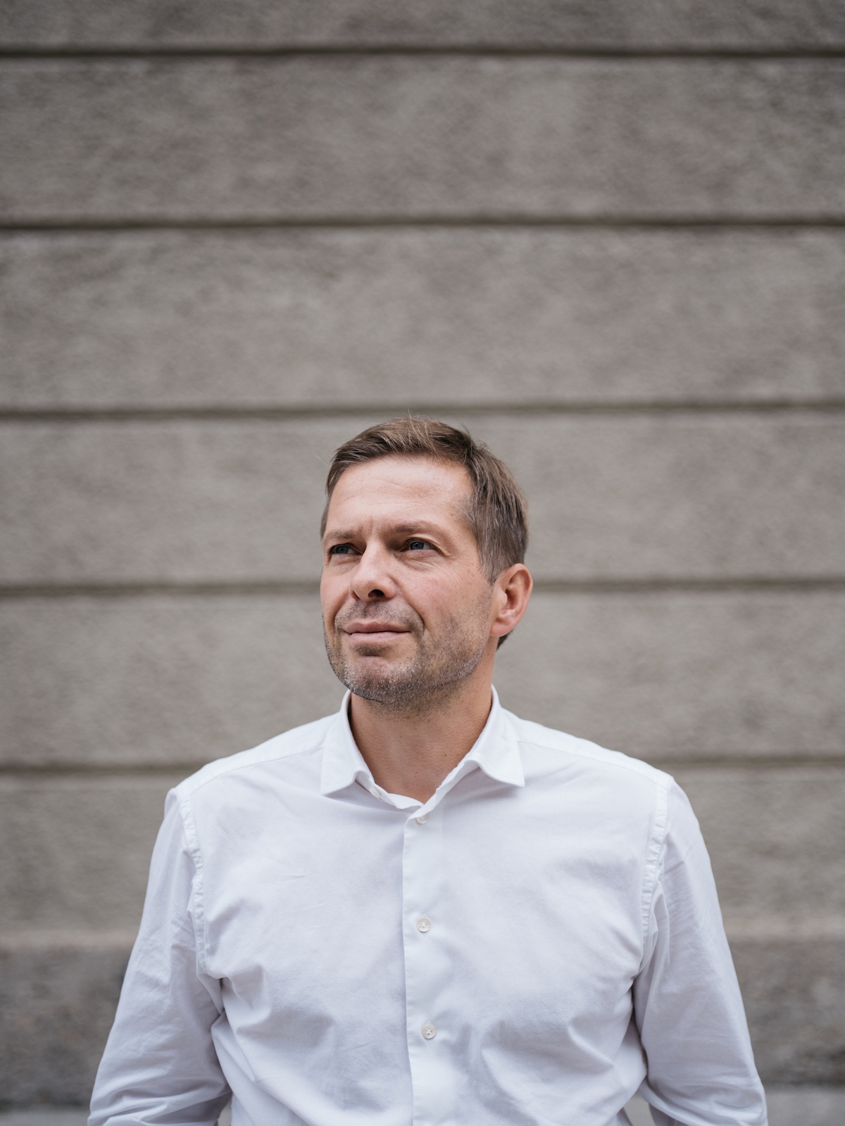 Andreas Gfrerer wearing white shirt against timber plank backgroud | Owner fo the Blauegans Hotel in Salzburg Austrai | Manmade: 12 Hotels Shaped by Men of Design and Style