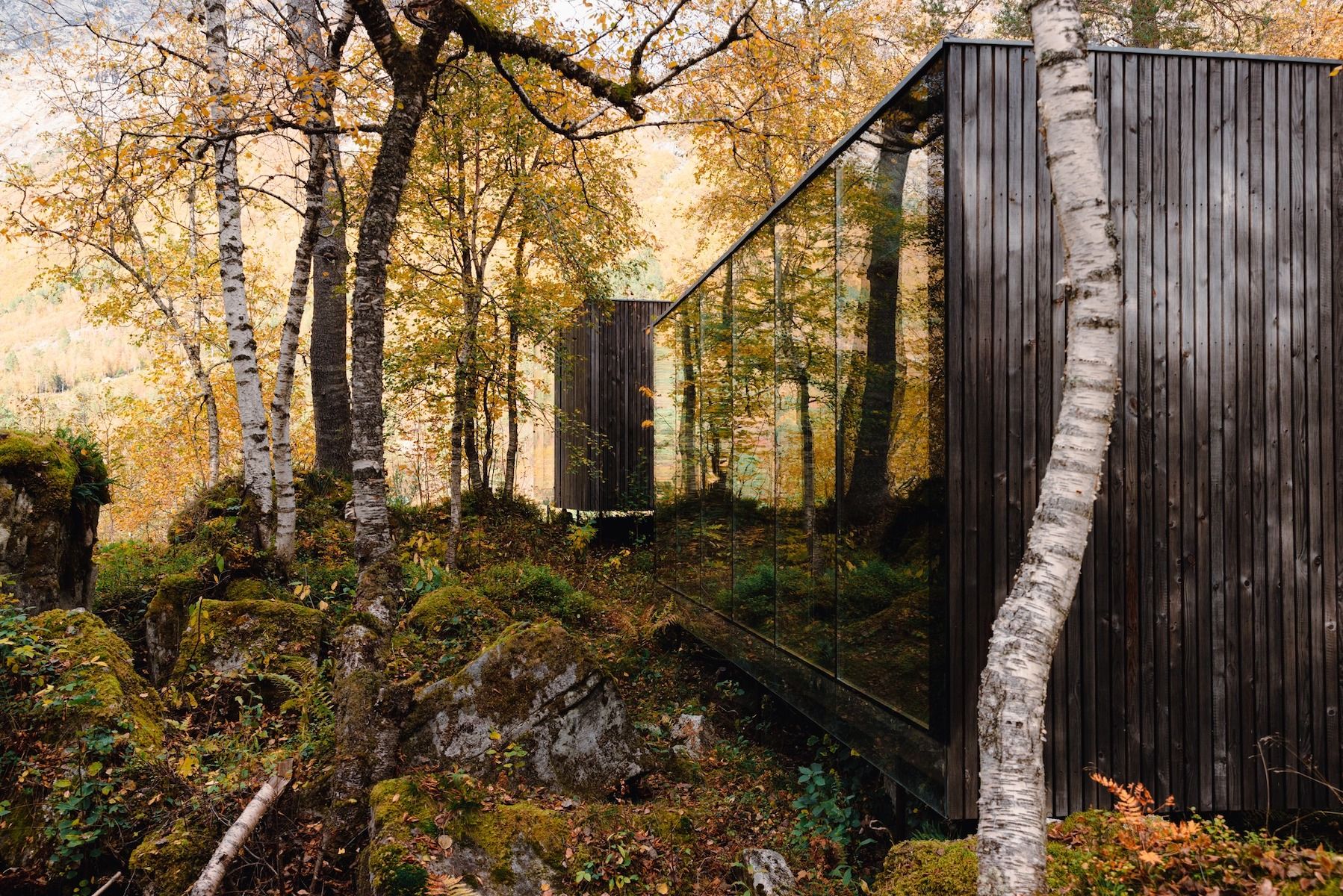 Charred timber and mirrored glass cabin among autumn birches above the Gudbrandsjuvet gorge, by Jensen & Skodvin | Juvet Landscape Hotel, Valldal, Norway | The Aficionados