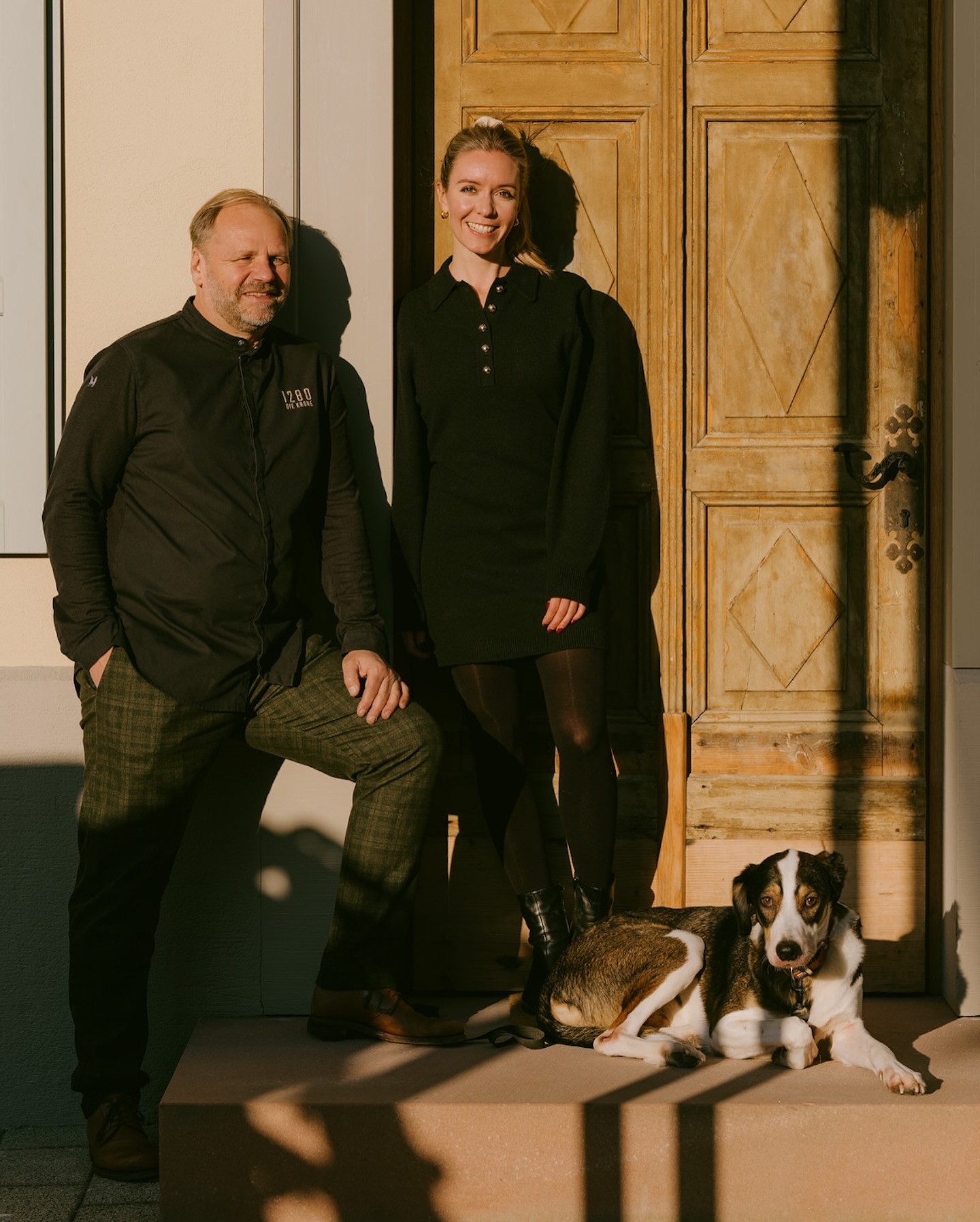 Couple of poeple stnading at the door entrance with thier dog/hound outside the KRONE Hotel in Germany |Poetic Design Hotels & Creative Hideaways Across Europe – The Aficionados