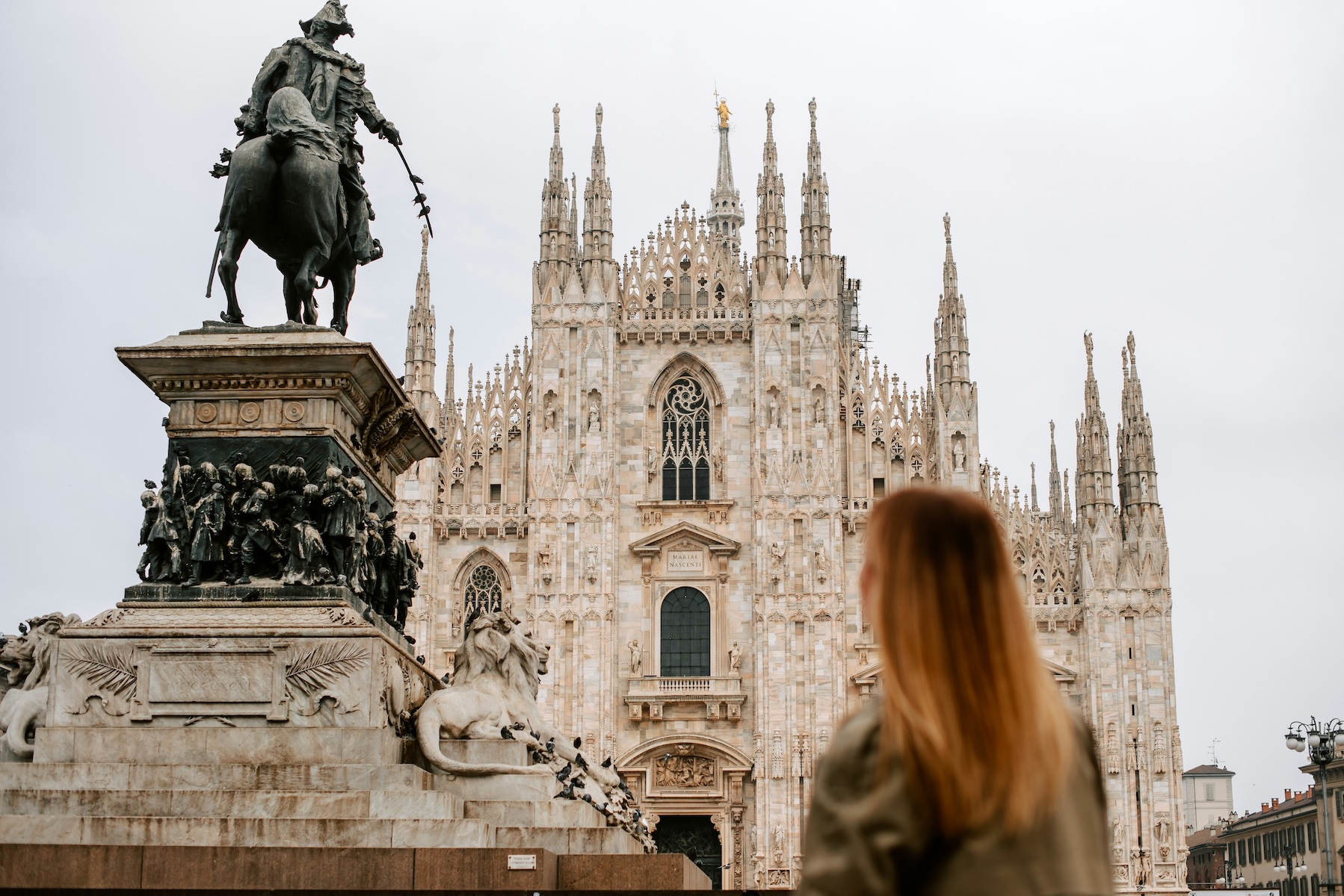 Woman gazing across Piazza del Duomo at Milan's Gothic cathedral and the Vittorio Emanuele II statue