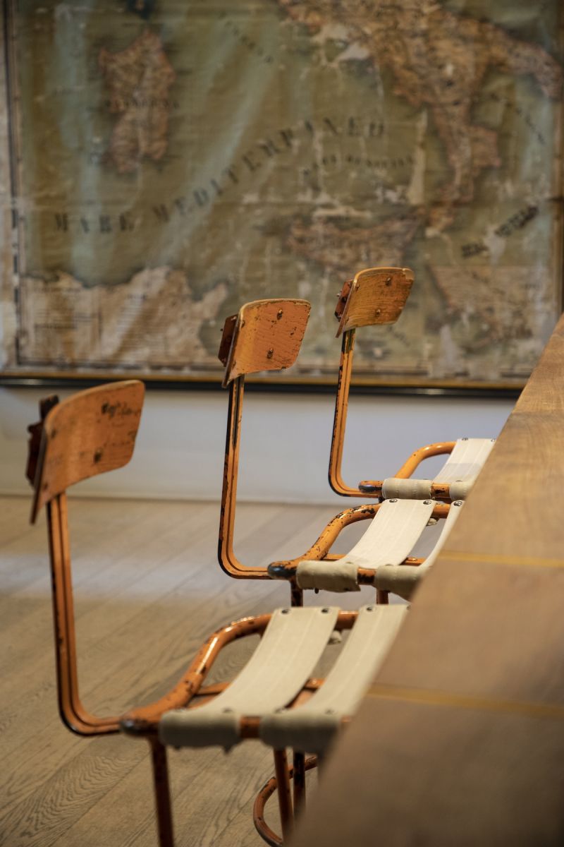 Vintage copper-framed chairs with canvas seats at La Bandita Townhouse, beneath an antique map of the Mediterranean | The Aficionados