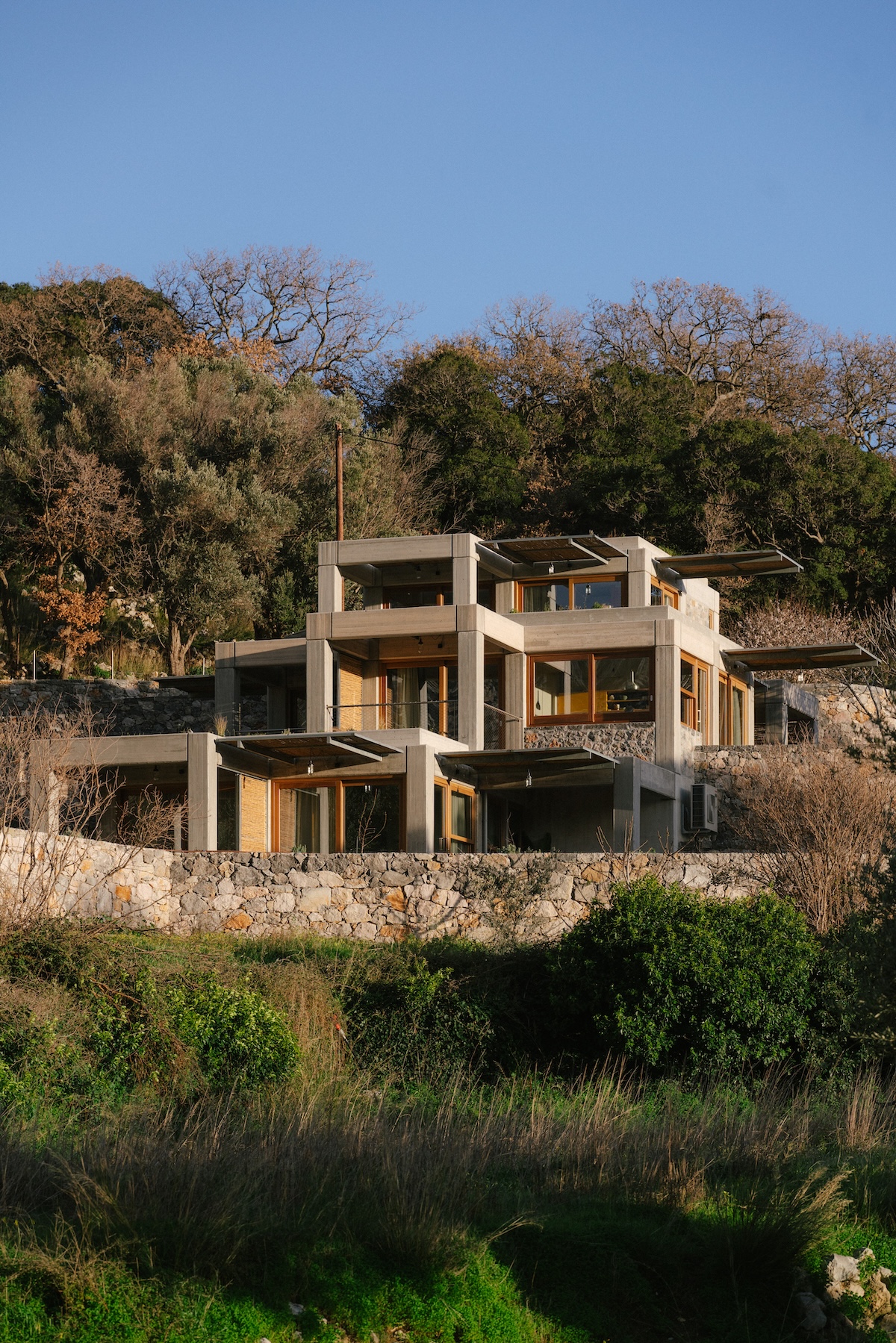 Meraki Studios' stacked concrete-and-timber apartments above a dry-stone wall on the terraced Cretan hillside | The Aficionados