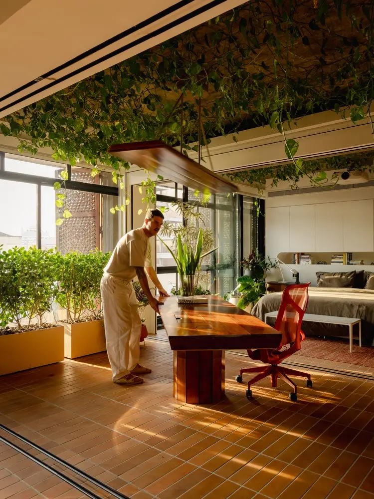 Designer working at a solid wood desk surrounded by trailing indoor plants, Lisbon Design Week 2026