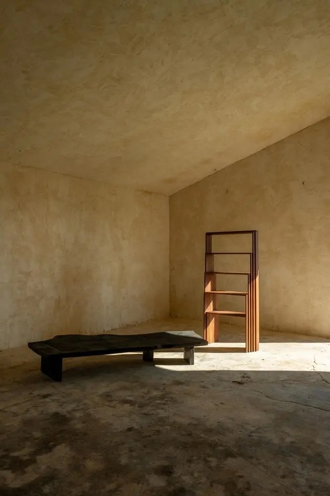 Burnt wood bench and handcrafted timber shelving in a raw plaster interior, Lisbon Design Week 2026