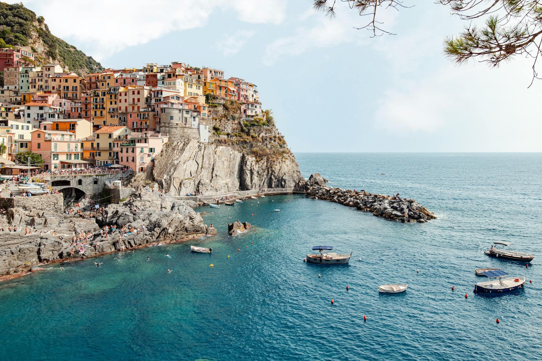 Colourful cliffside houses of Manarola tumbling down to a boat-filled harbour on the Ligurian coast, Italy