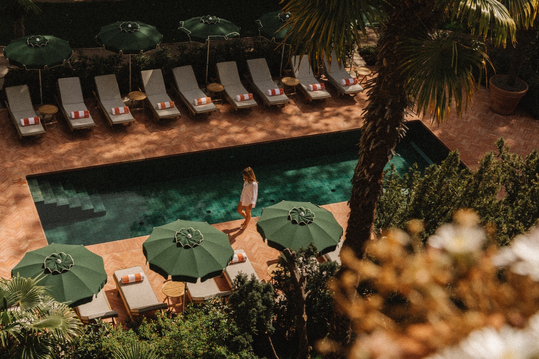 Beautiful outdoor pool design lined with stripped loungers and parasols, vegetations and teracotta tiles |South Tyrol Hotels by the Dissertori Brothers | Design & Architecture