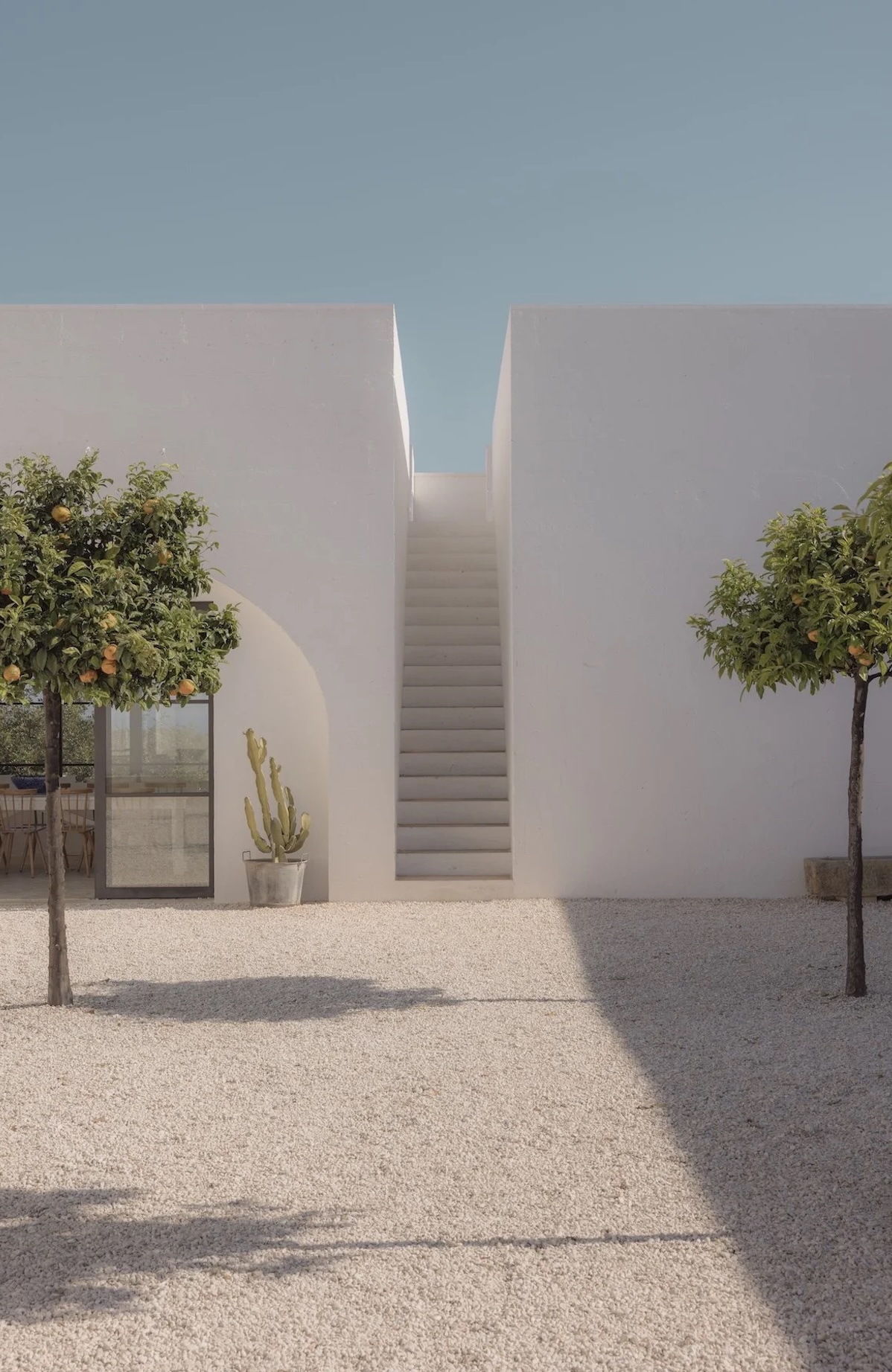 The whitewashed courtyard of Masseria Moroseta in Puglia, twin citrus trees flanking an external limewashed staircase | The Aficionados