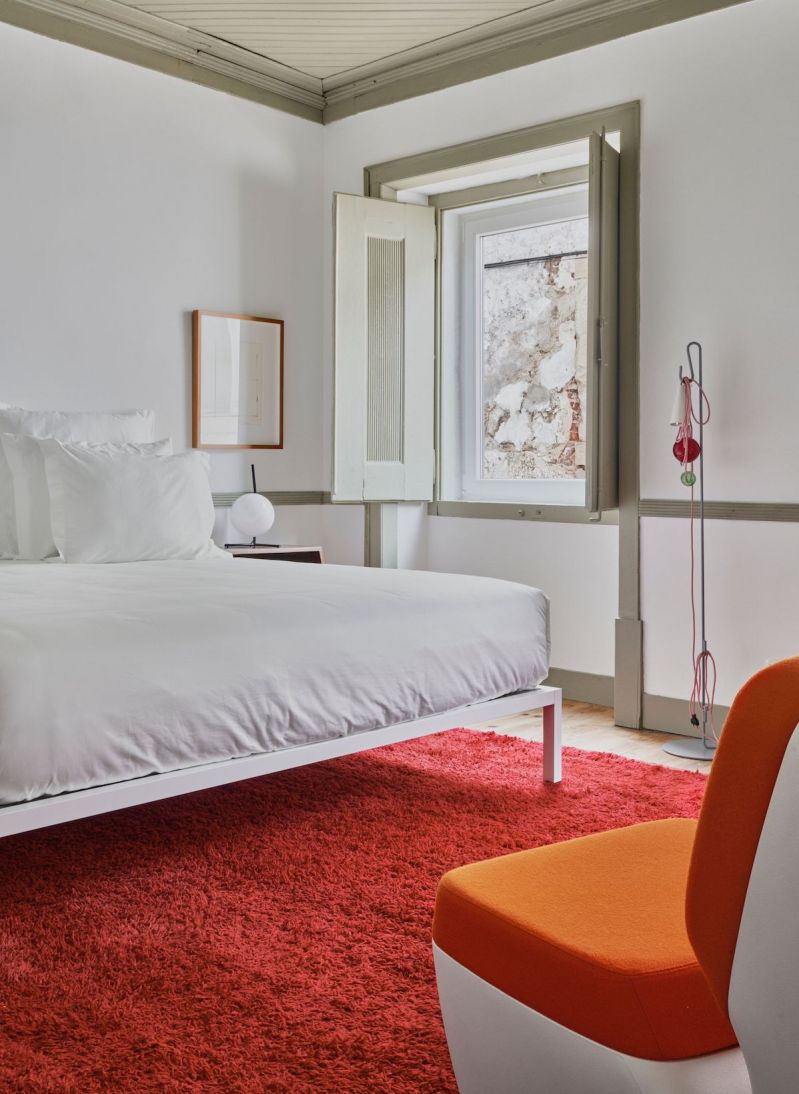 Casa Fortunato, Alcácer do Sal, Alentejo: bedroom with Mizzle-green joinery and red rug in a hundred-year-old townhouse, by architects António and Filipa.