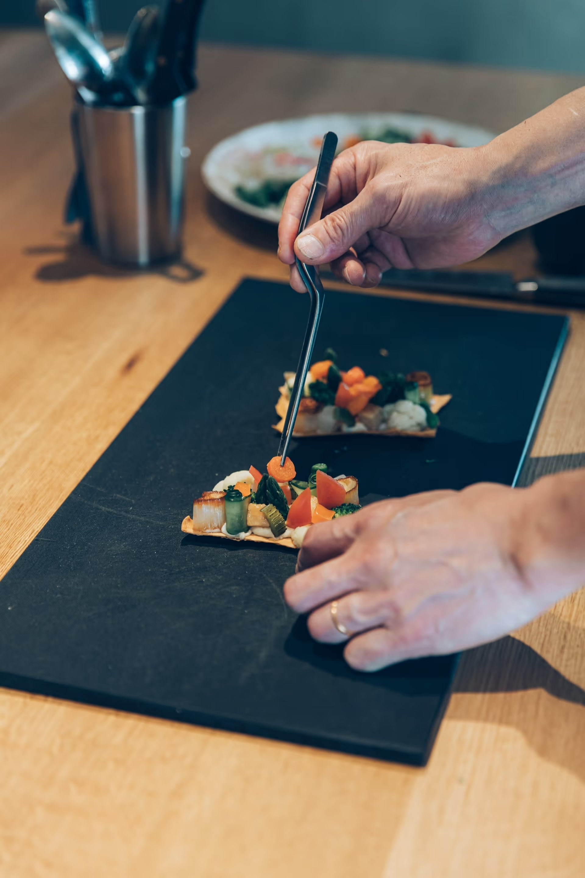 Makoto Fuse placing vegetables with tweezers onto a thin crisp at Auberge Né | The Aficionados