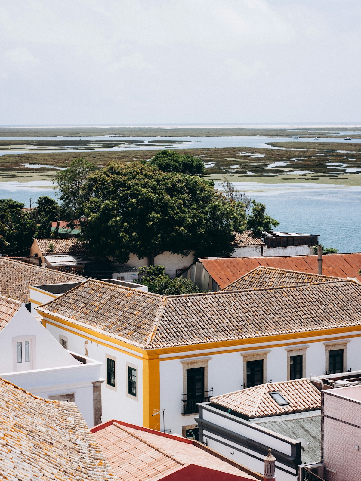 Historic fishing village with teracotta rooftops and distant sea |Ria Formosa to Ilha de Tavira – Nature, Culture & Design in the Algarve