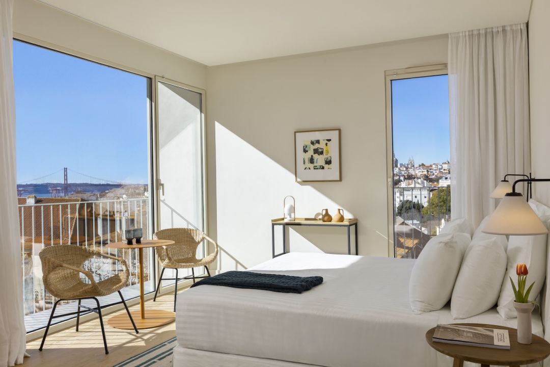 Design-hotel bedroom at the Boutique hotel Pátio do Tijolo in Lisbon with a private balcony framing the Tagus and the 25 de Abril bridge