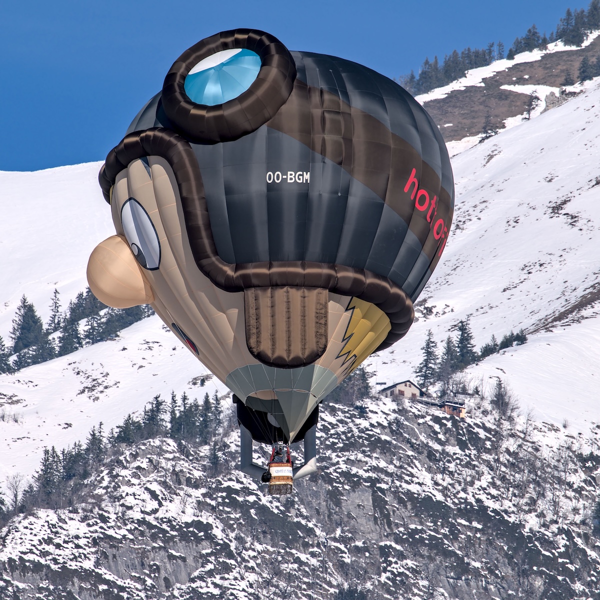 A colourful photo of Switzerland's famous hot air balloon festival, blue sky and balloons in it