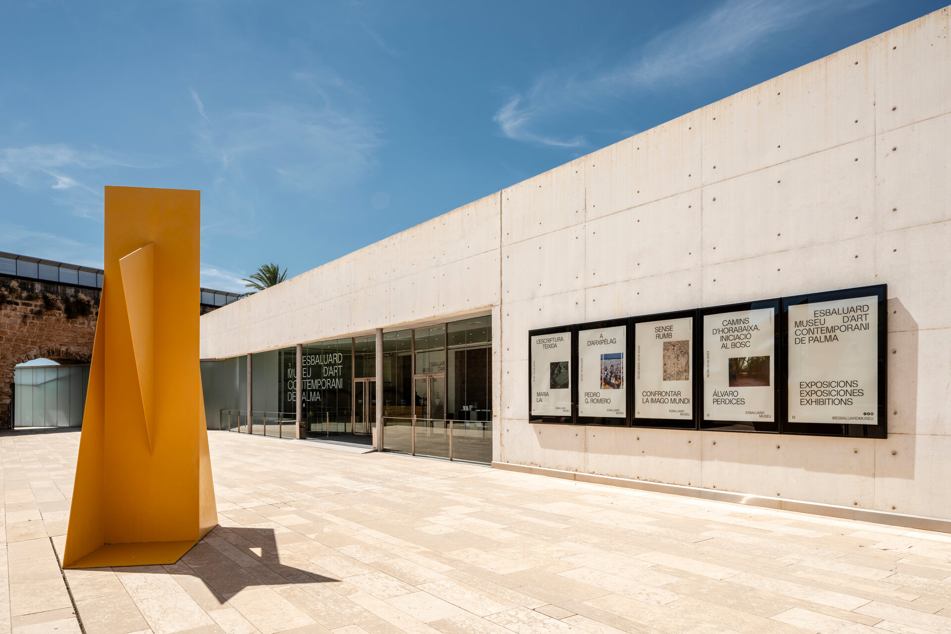 The board-marked concrete façade and glazed entrance of Es Baluard, with a yellow steel sculpture in the forecourt | The Aficionados