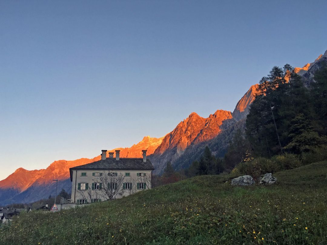 Patrician Villa house in Stampa at sunset, stone facade below alpenglow on the jagged Bregaglia peaks, Graubünden.