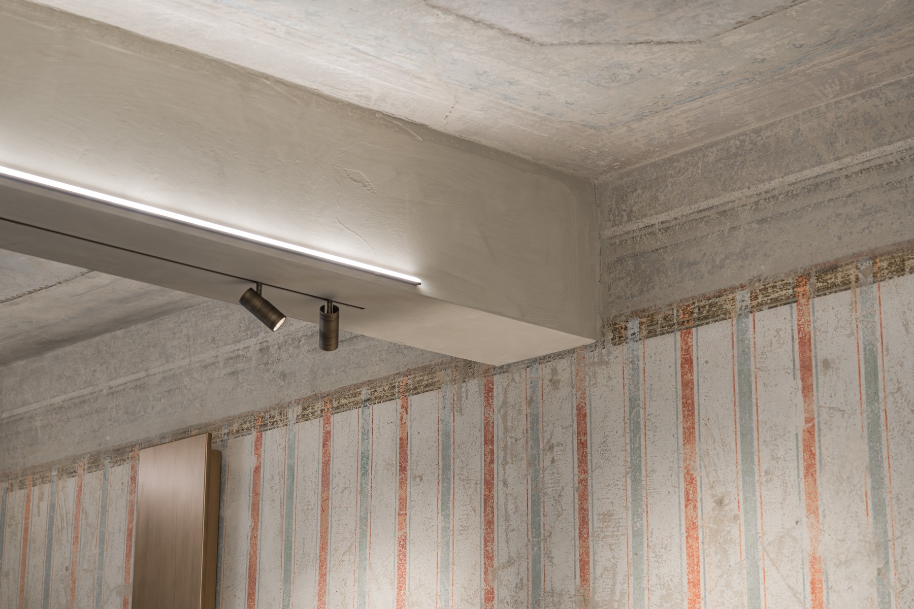 ecovered wall painting at Santa Croce Historical Home, faded stripes of red and sea green running beneath a plastered beam and painted cornice. © Tommaso Pini