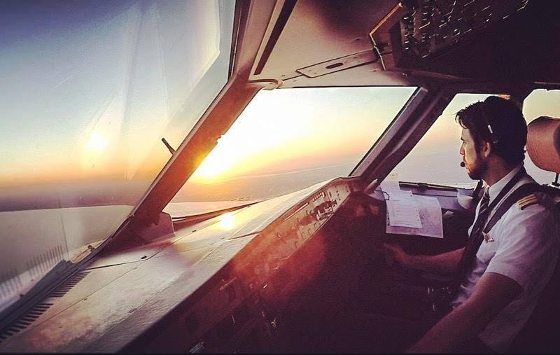 TAP Air Portugal captain Ricardo Nunes at the controls of an airliner flight deck, the sun low on the horizon through the cockpit windscreen.