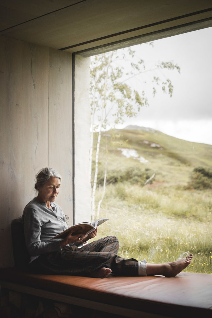 woman sitting in the Window seat Design overlooking the Highlands of Scotland | Window seat box | timber | Ruth Kramer: Interior Designer Behind Brücke 49 & Wildland