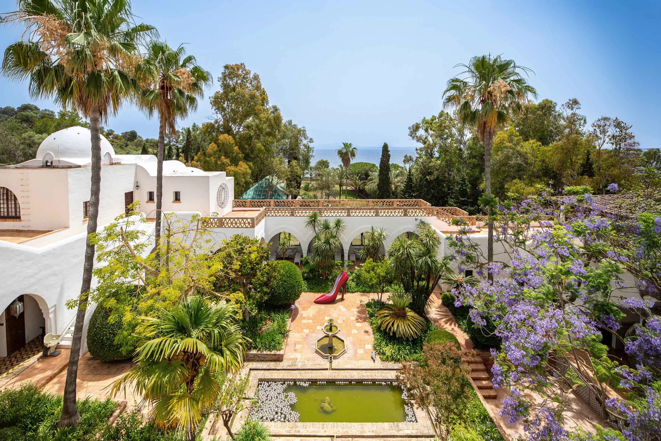 The central courtyard at Sa Bassa Blanca, with whitewashed Moorish arches, jacaranda and a lily pond above the sea | The Aficionados