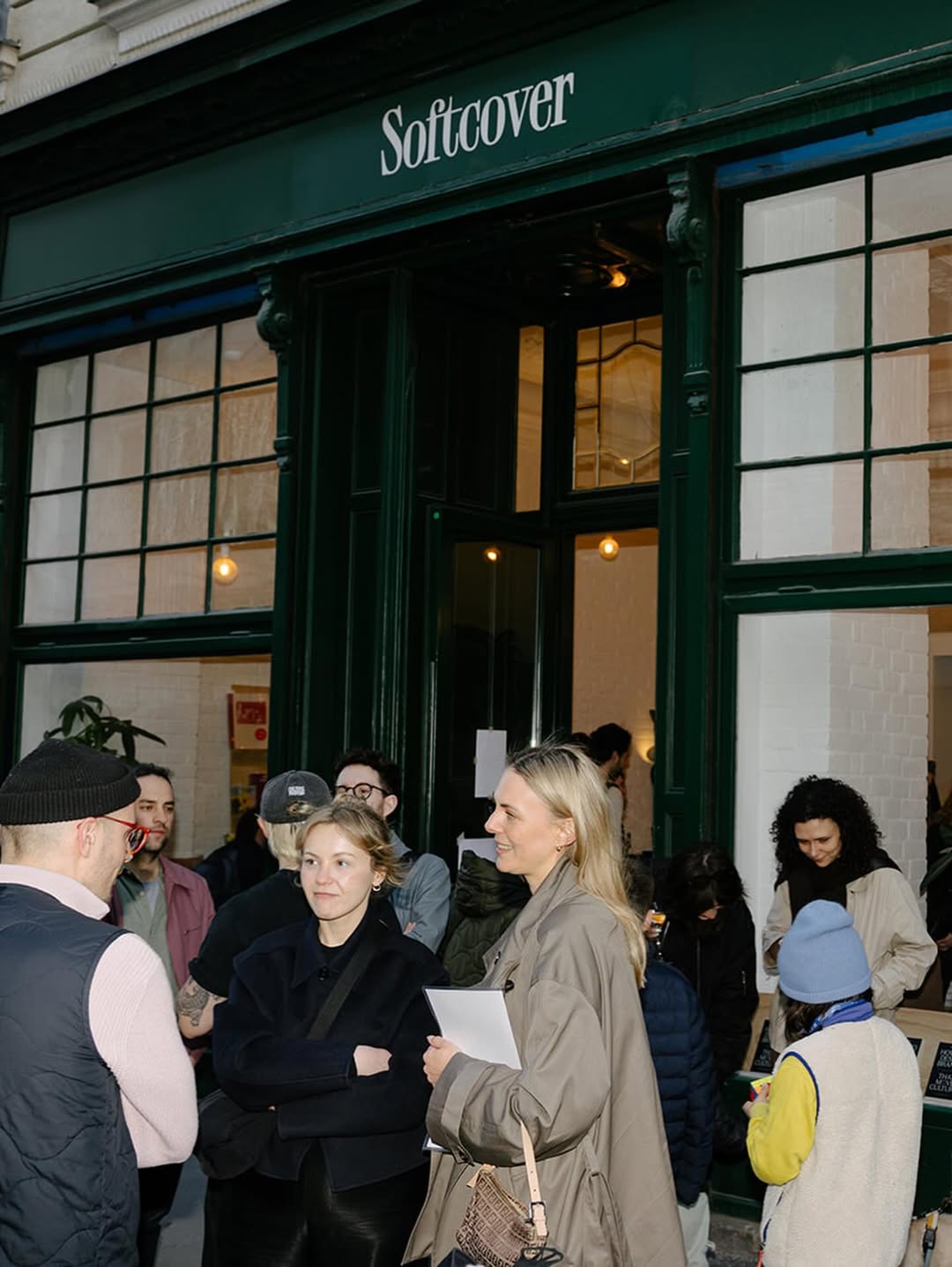 Evening crowd gathered outside the green Softcover shopfront during an event in Vienna's sixth district.
