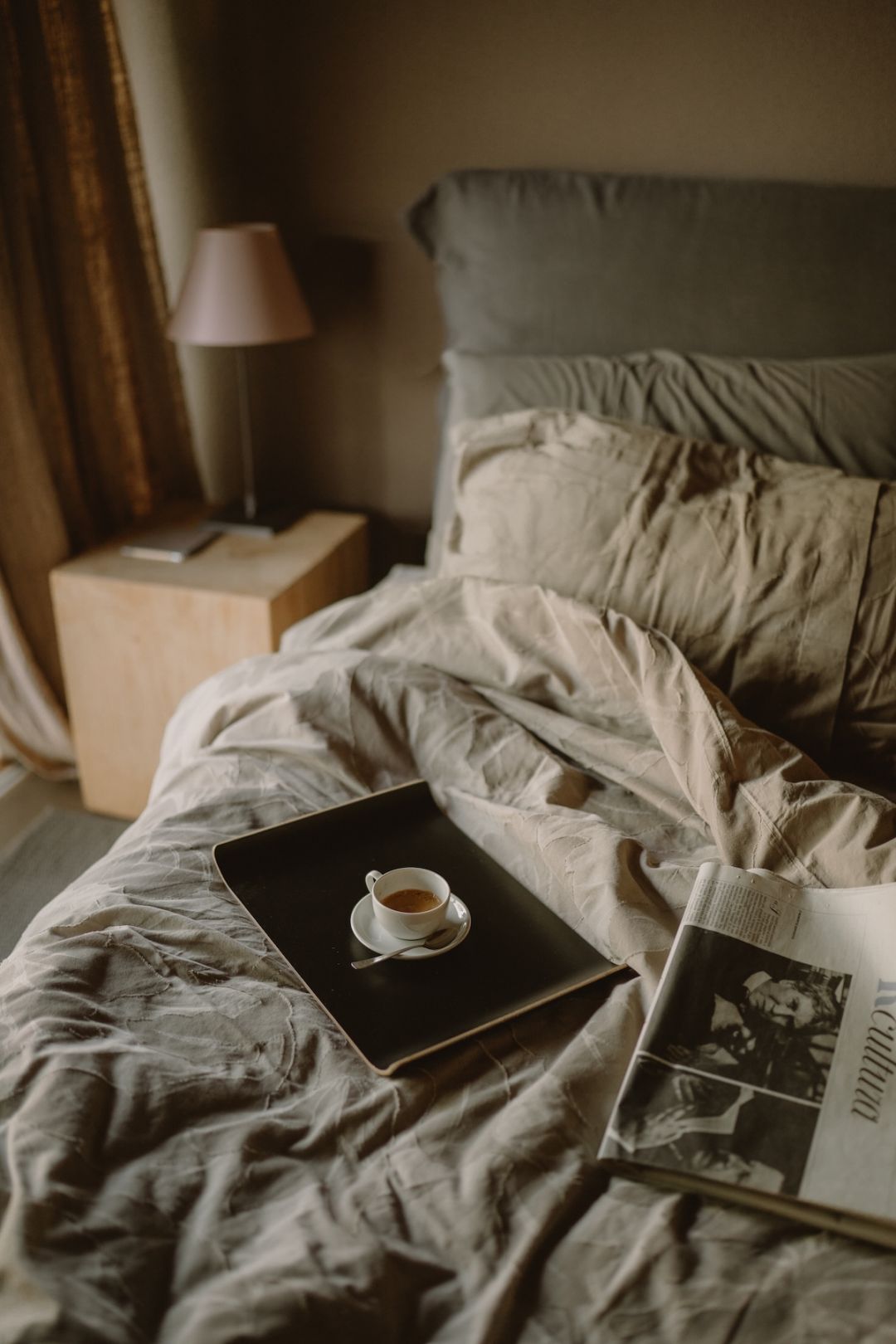 Morning-after calm in a Lake Garda design hotel: linen bedding, an espresso on a black tray and a newspaper, the reward for a race well run.