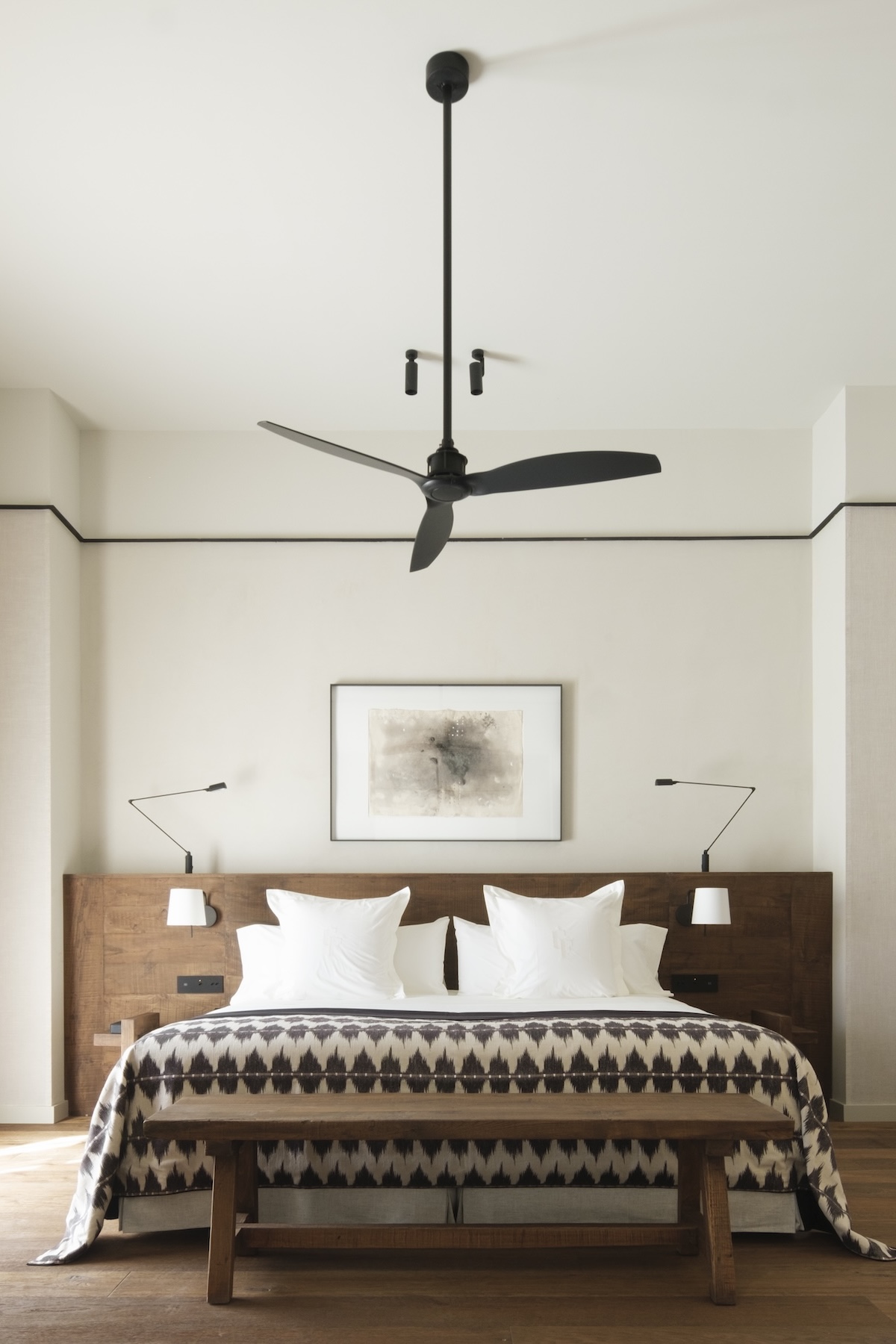 Guest room at Can Ferrereta with a dark-wood headboard, ikat throw and black ceiling fan | The Aficionados