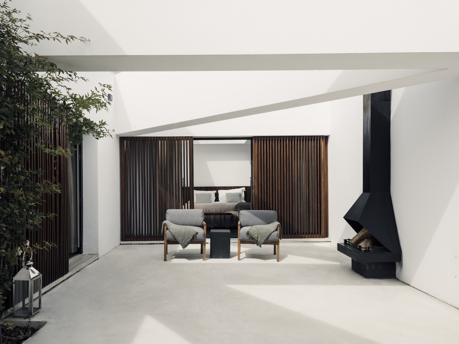 L'AND Vineyards, Alentejo: Sky Suite patio with timber screens, sculptural black fireplace and lounge chairs, architecture by Márcio Kogan (Studio MK27).