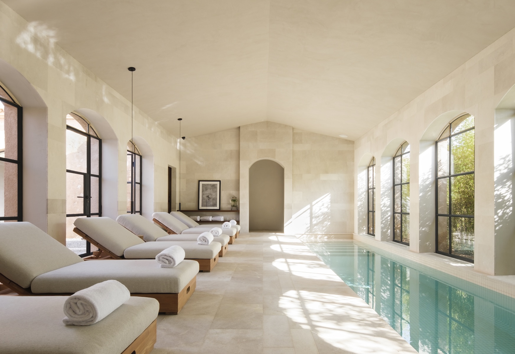 Indoor pool at Sa Calma spa, Can Ferrereta, with arched Crittall windows and stone loungers | The Aficionados