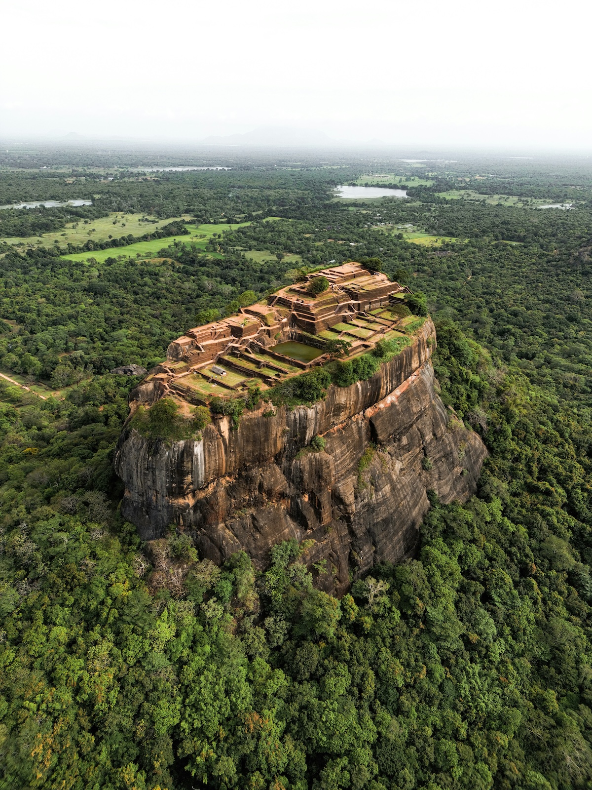 Aerial view of the summit ruins of Sigiriya rock palace above the surrounding plains, Sri Lanka | The Aficionados