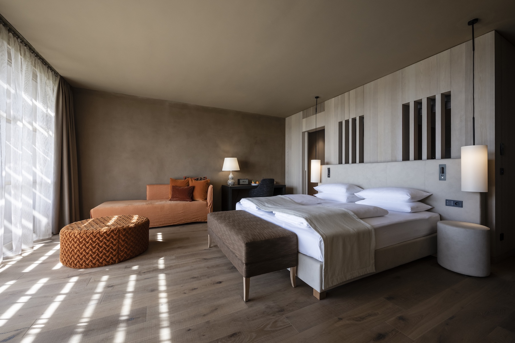 Guest room at ADLER Spa Resort Sicilia with burnt-orange furnishings, oak floors and a limewashed headboard wall | The Aficionados