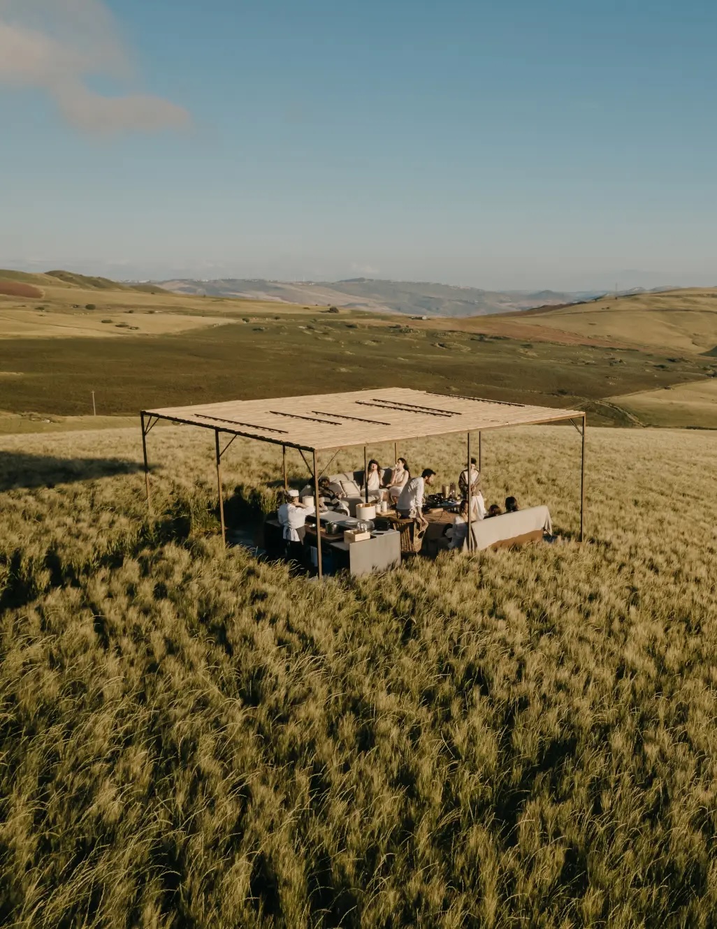Open-air dining in the wheat fields of the Susafa estate, soil-to-table experience among the working crops of the Saeli-Rizzuto masseria, regenerative-farming boutique hotel in the Madonie, Sicily | The Aficionados.