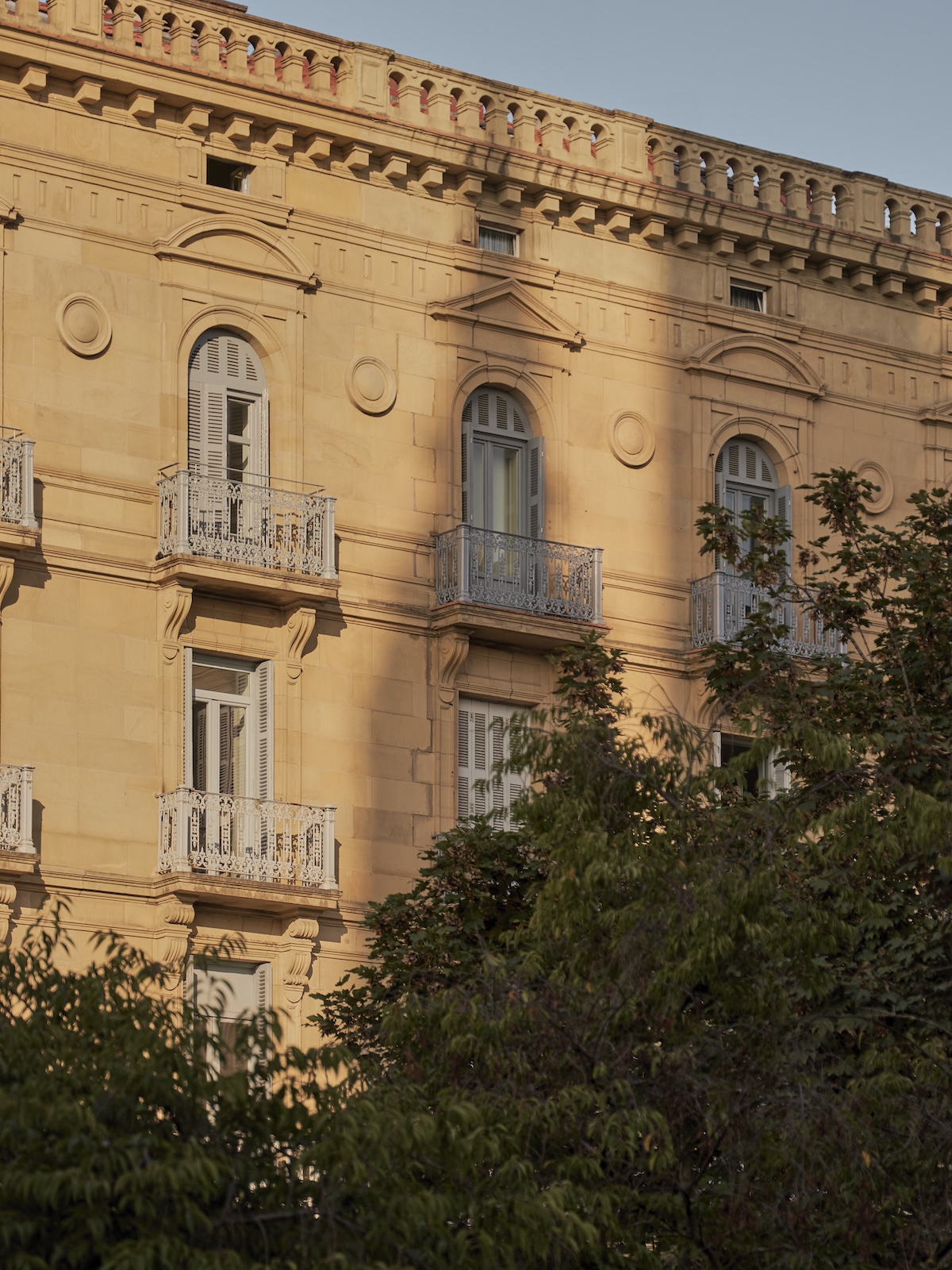 Hotel Arbaso's neoclassical ashlar façade with wrought-iron balconies and arched shutters at golden hour, San Sebastián | The Aficionados