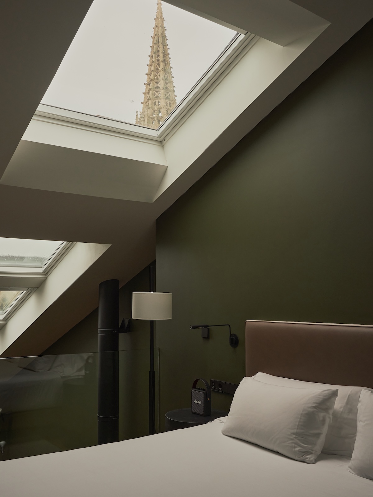 Bedroom at Hotel Arbaso with the Buen Pastor spire framed in the skylight above a leather headboard | The Aficionados