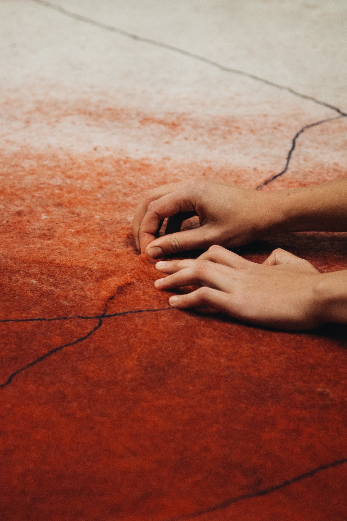 Hands smoothing a panel of natural rust-toned felted fibre at Atelier LUMA, Arles | The Aficionados