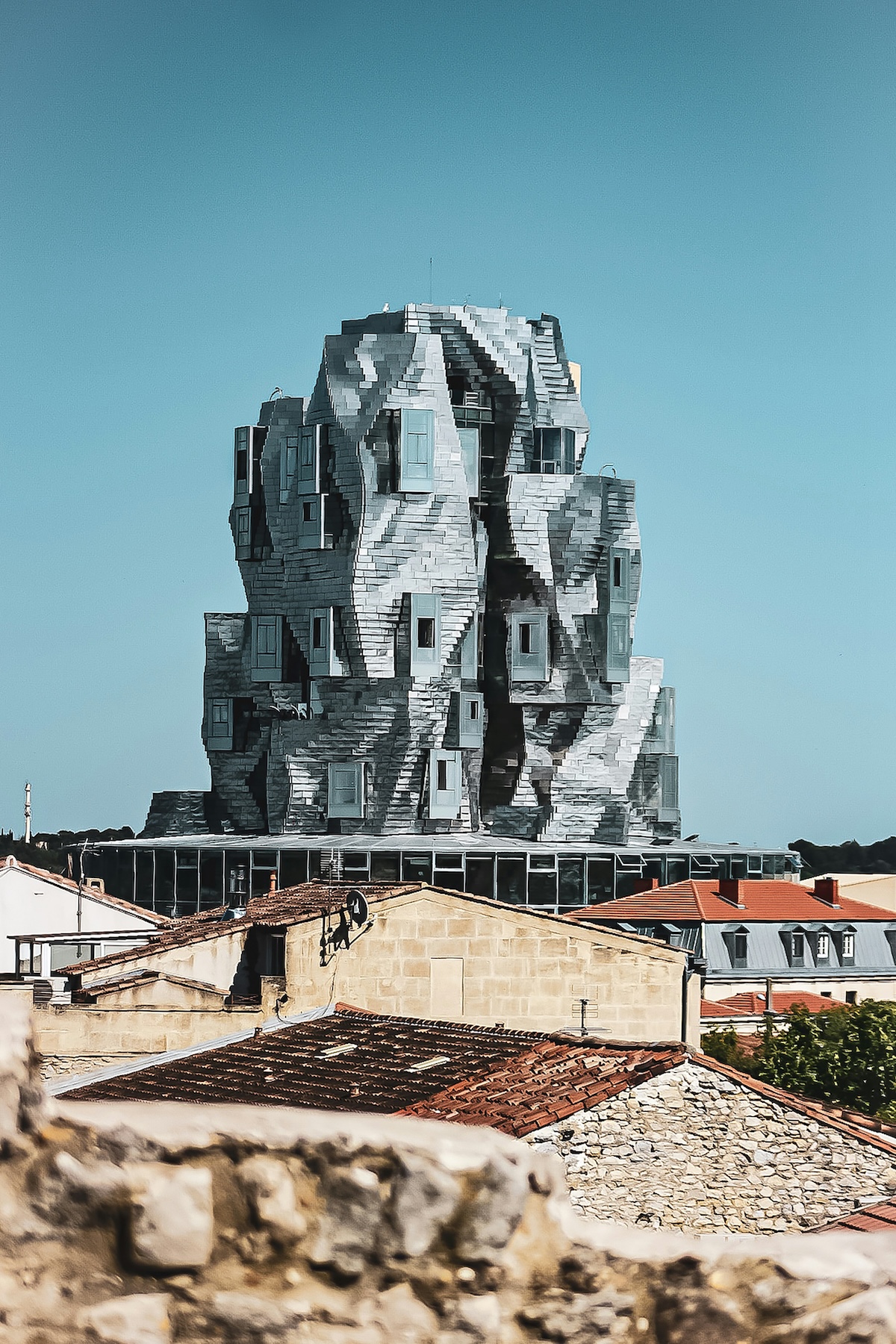 The twisting aluminium-clad LUMA tower by Frank Gehry seen above the terracotta rooftops of medieval Arles | The Aficionados