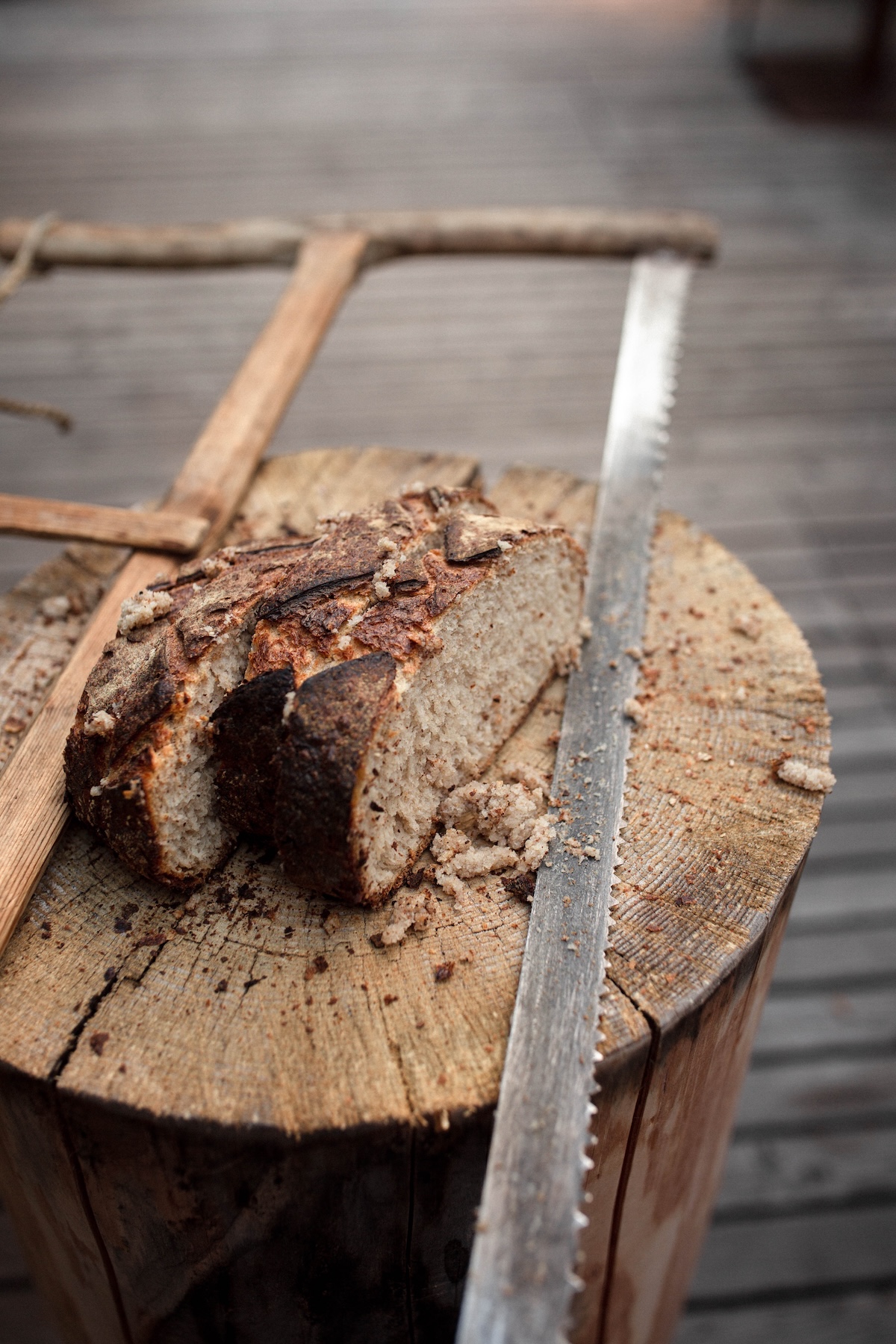 Dark sourdough sliced on a birch stump with the old carpenter's bow saw, the signature opening to dinner at Christoph Huber's Blaue Traube | TheAficionados.com