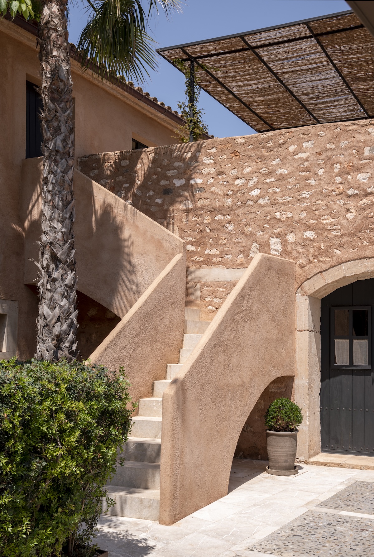Sculptural rendered staircase and stone arch in a courtyard at Can Ferrereta, Mallorca | The Aficionados
