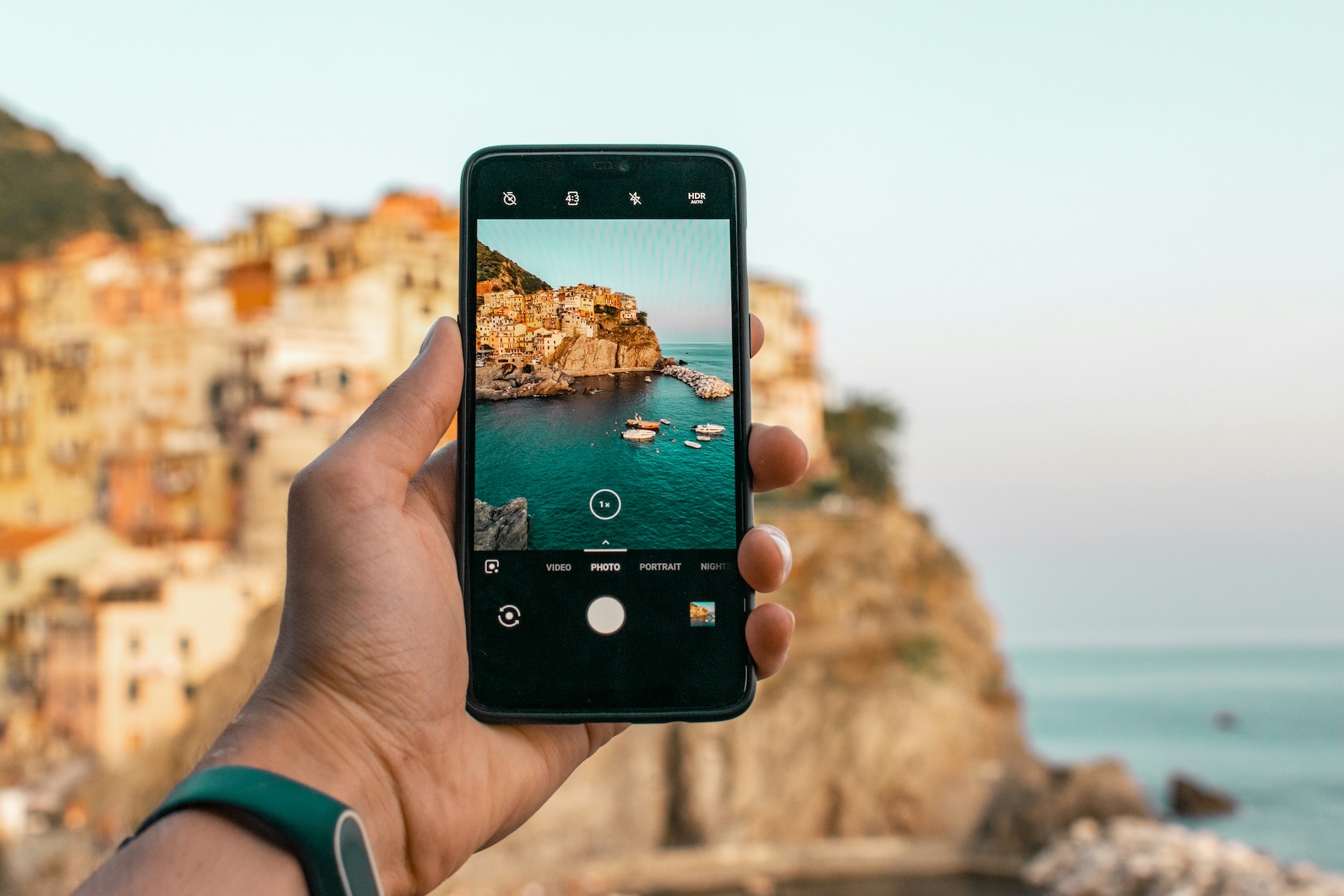 Colourful cliffside houses of Manarola tumbling down to a boat-filled harbour on the Ligurian coast, Italy