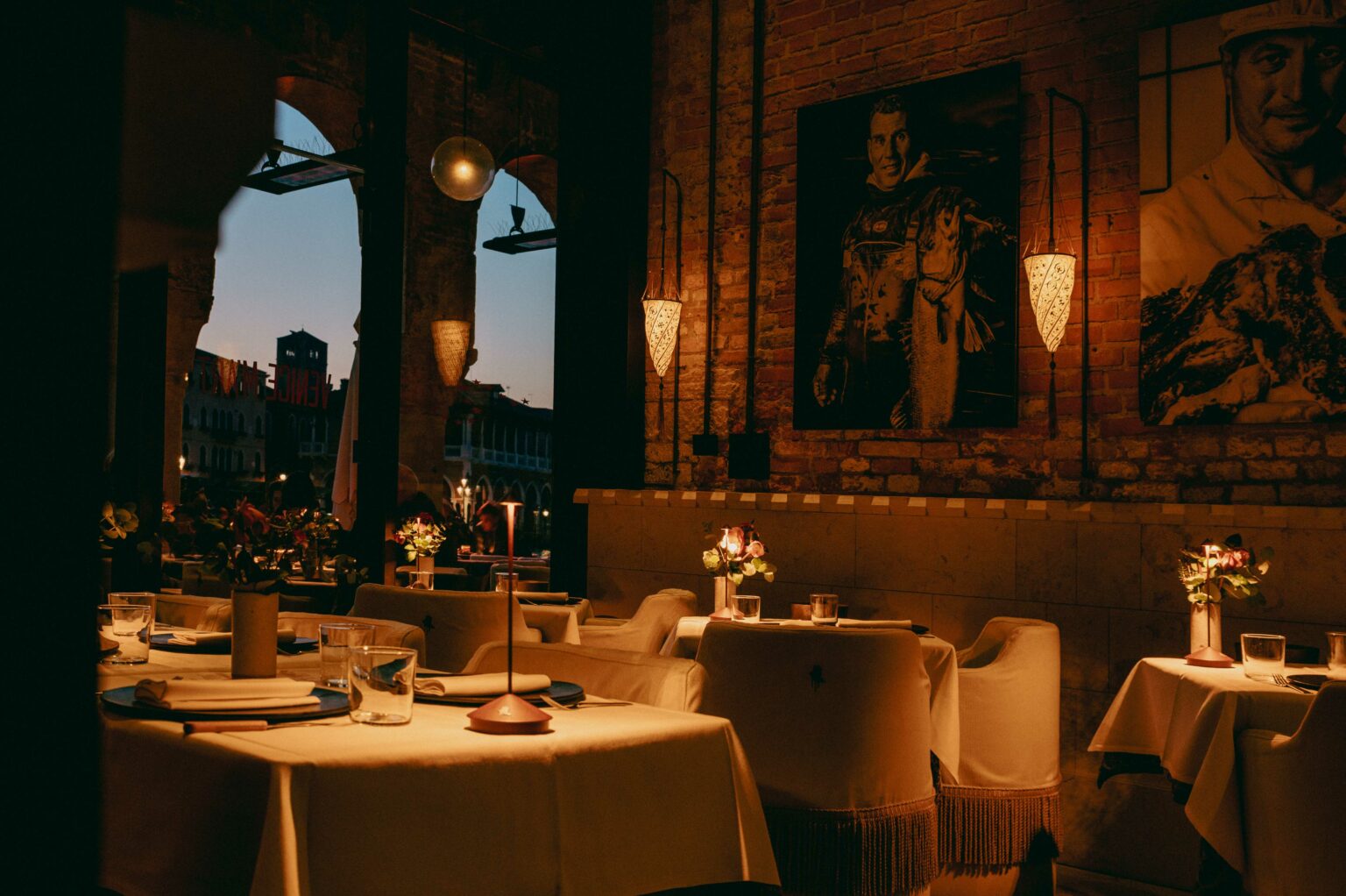 Francy's dining room with a black-and-white portrait of a fisherman, Fortuny lanterns and canal views at dusk.