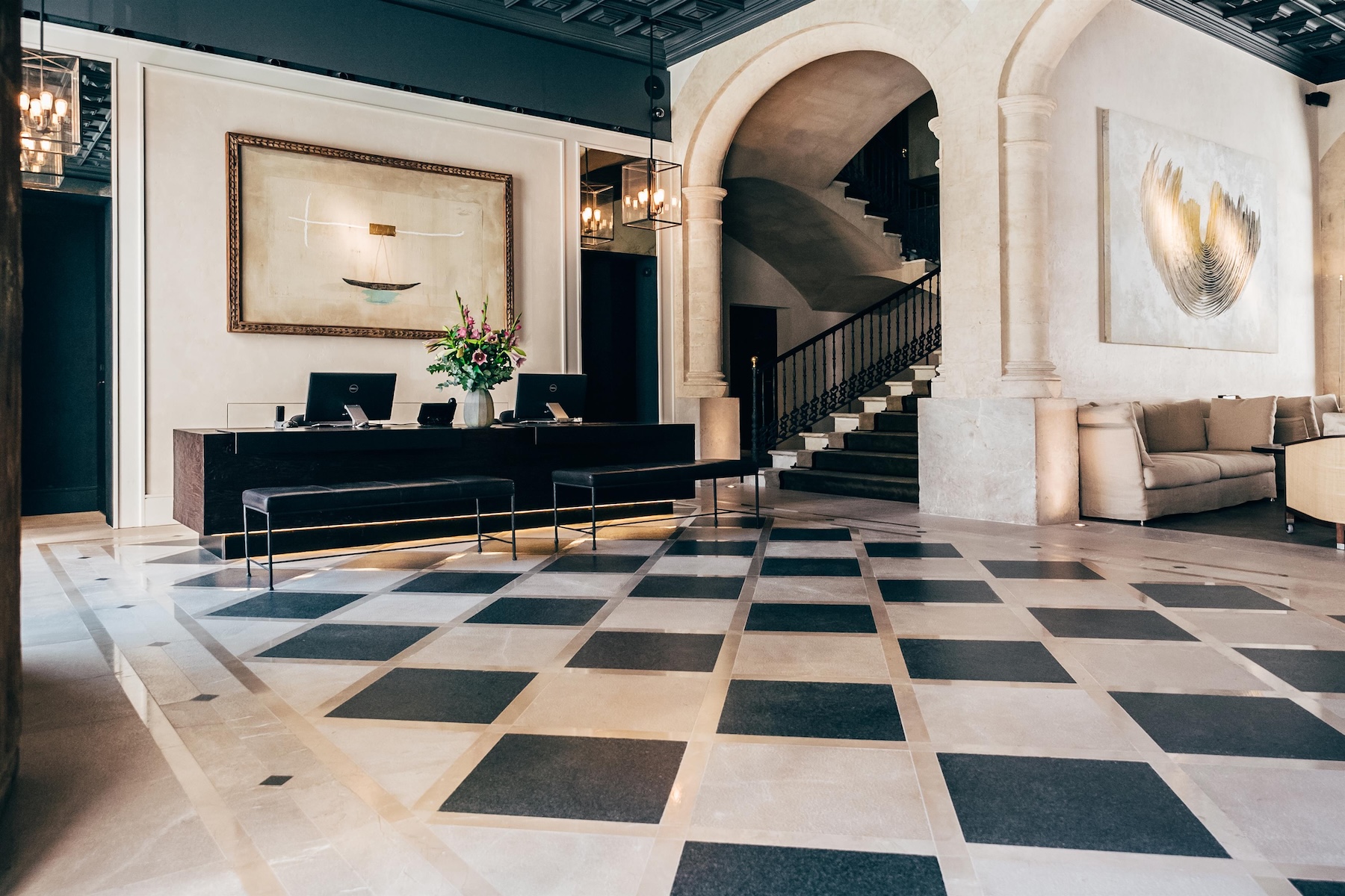 Lobby at Sant Francesc Hotel with black-and-white checkerboard marble floor, wrought-iron staircase and commissioned art, Palma | The Aficionados