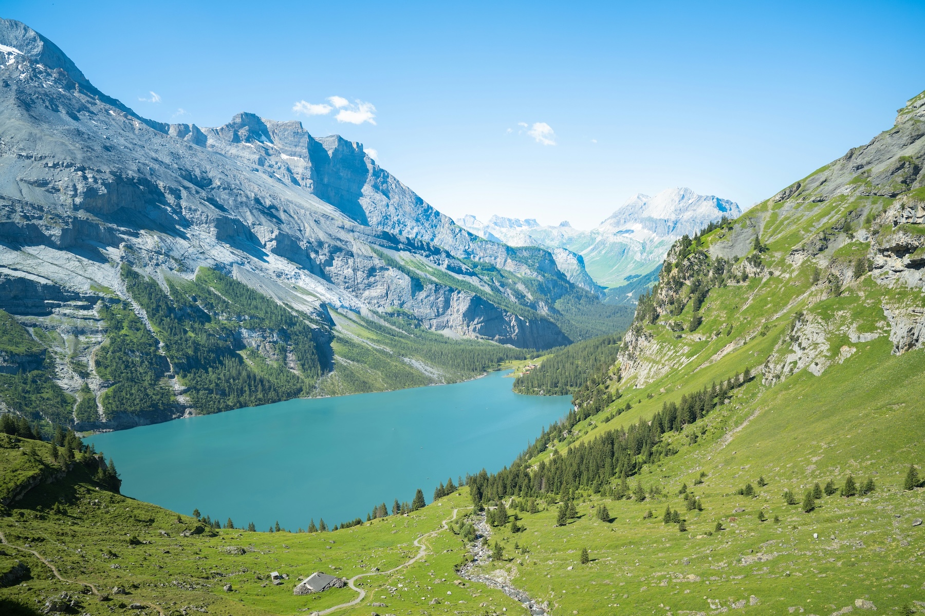 Turquoise Oeschinensee lake ringed by grey peaks and green Alpine slopes above Kandersteg, Bernese Oberland, Switzerland.