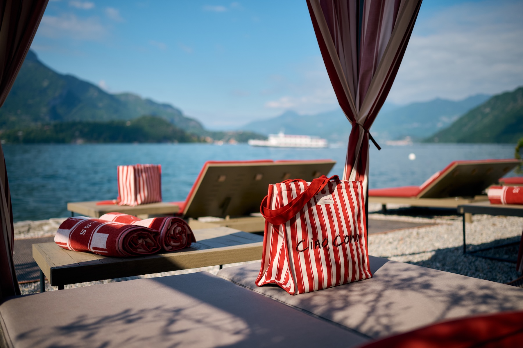 GUESS Ciao Como striped tote bag and red beach towels on Filario cabana lounger, Lake Como ferry crossing, Lezzeno waterfront, Italian design hotel | TheAficionados.com